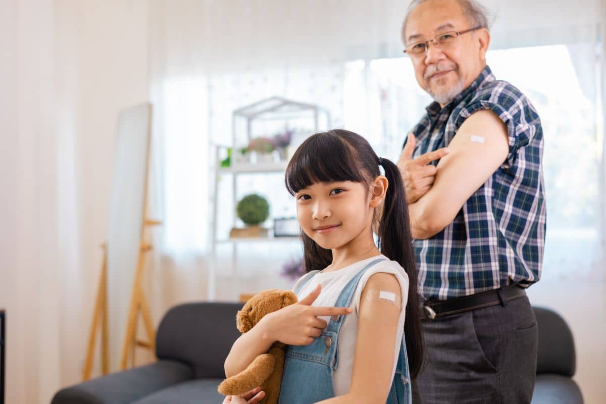 A young girl and adult man demonstrate they have received a vaccine.